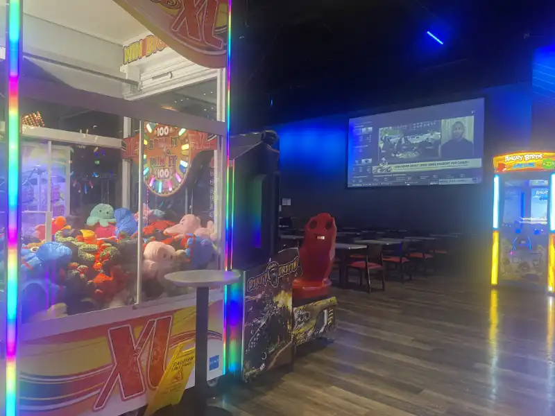 Jake's Unlimited - a game room with a large screen and a toy machine.