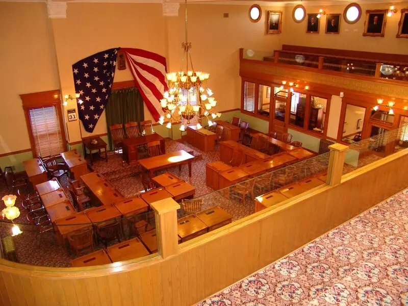 A large courtroom with an american flag hanging from the ceiling.