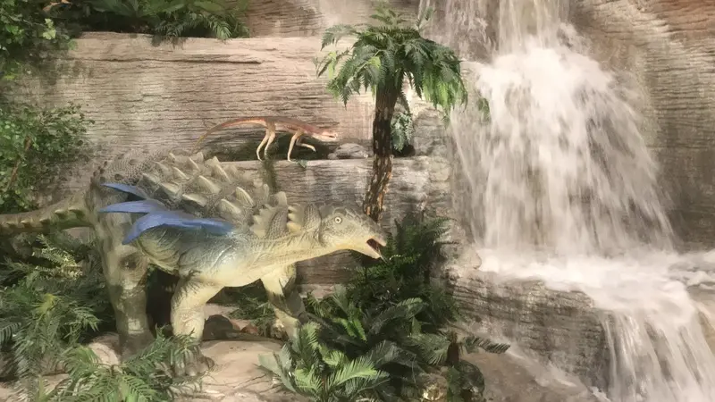 The dinosaurs are in front of a waterfall.