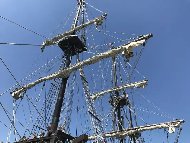 A tall ship is docked next to a blue sky.