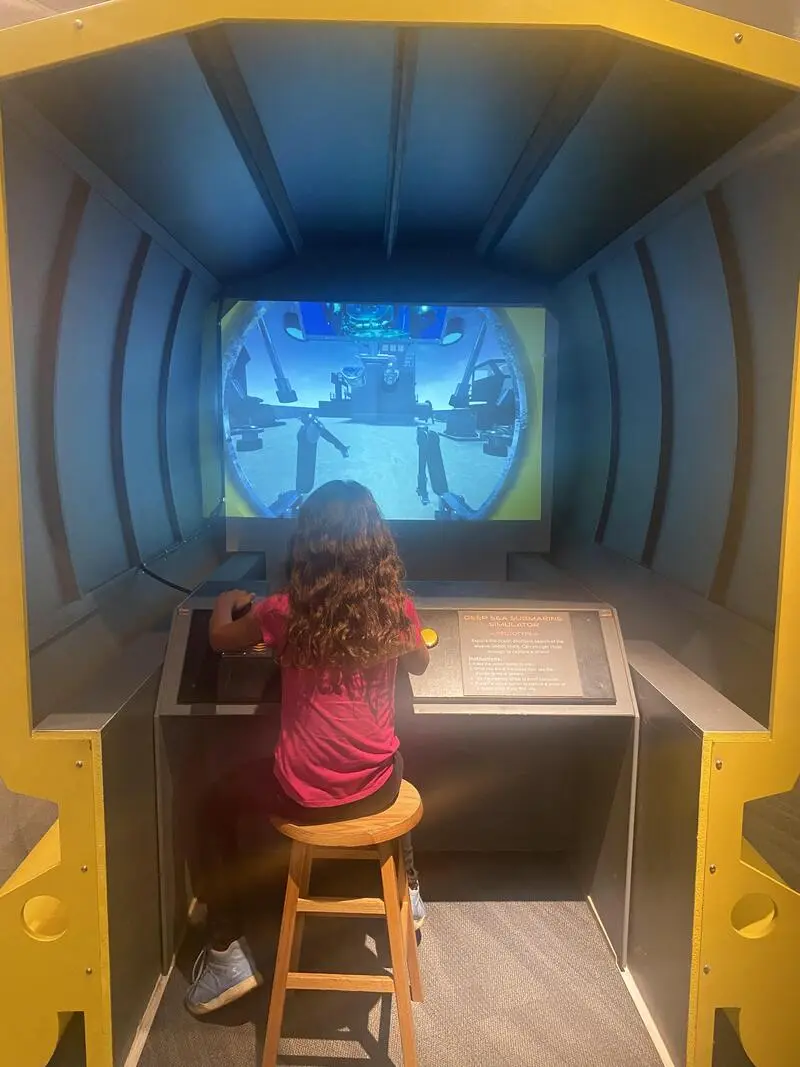 A little girl playing a video game in a museum.