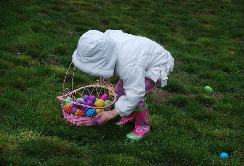 girl in white hoodie hunting eggs during Easter