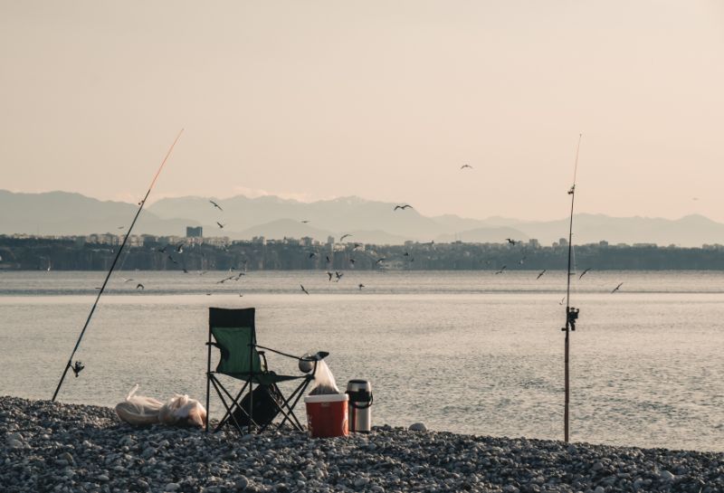 fishing rods near empty chair on shore