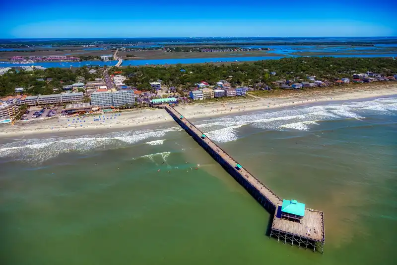 An aerial view of the beach and pier at Folly Beach in Charleston