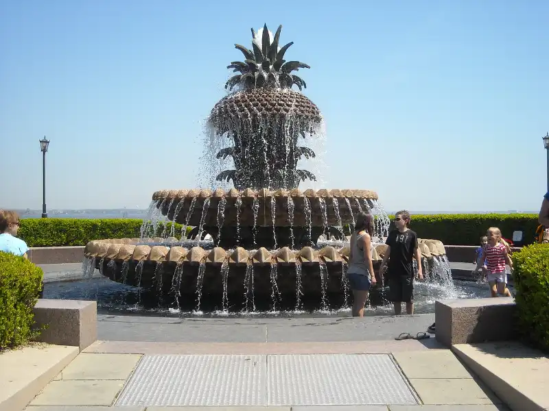 A group of people standing near a pineapple fountain.