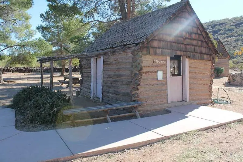 A small log cabin with a bench in front of it.