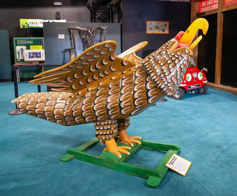 A wooden eagle statue is on display in a museum.