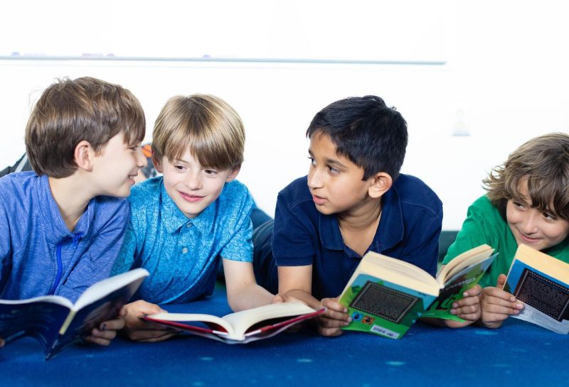 An image of young boys reading books and chatting