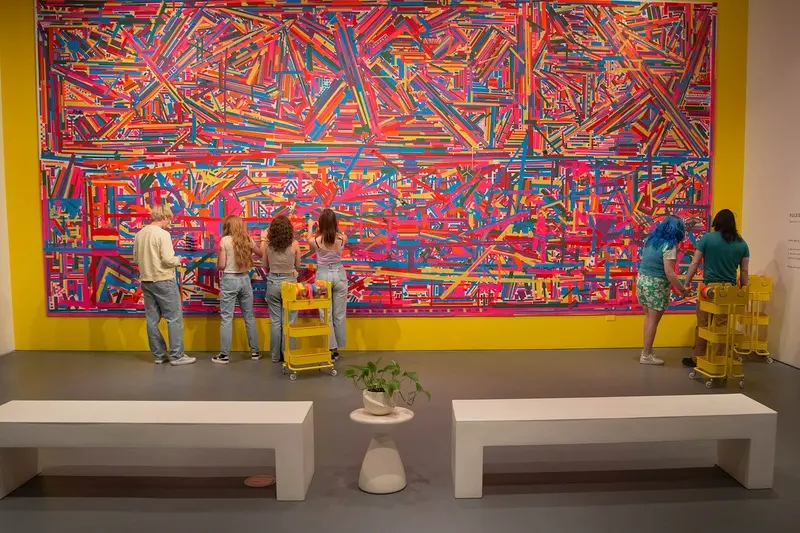 A group of people looking at a colorful painting in an art museum.
